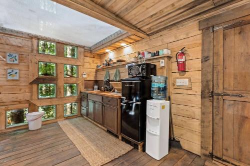 a kitchen with a black refrigerator and wooden walls at Treehouse - Amazonia - Red River Gorge KY in Rogers