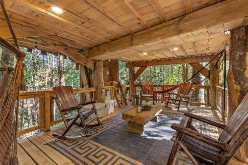 a log cabin with rocking chairs and a hammock at Treehouse - Amazonia - Red River Gorge KY in Rogers