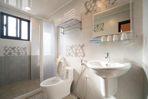 a white bathroom with a toilet and a sink at Sunny Breeze Penghu in Magong
