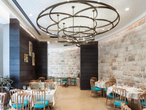 a dining room with tables and chairs and a chandelier at Legacy Hotel ַ& Convention Center Nazareth in Nazareth