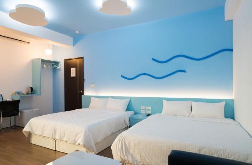 two beds in a room with a blue ceiling at Sunny Breeze Penghu in Magong