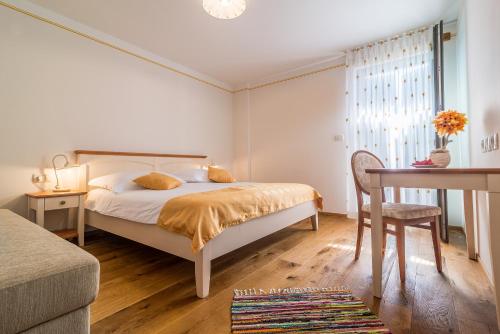 a bedroom with a bed and a table and a chair at Casa Krasna Gourmet Boutique Hotel in Lokev