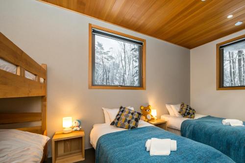 a bedroom with two beds and two windows at PHOENIX COCOON by Hakuba Hotel Group in Hakuba