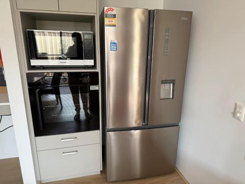 a stainless steel refrigerator with a microwave on top of it at Milbridge Getaway with a bathroom in each room in Eaton