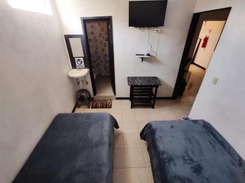 een kamer met 2 bedden, een wastafel en een televisie bij Hotelito Ejido in Sanctórum