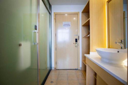 a bathroom with a sink and a glass shower at GreenTree Inn Shanghai National Convention and Exhibition Center Huaxiang Road in Shanghai