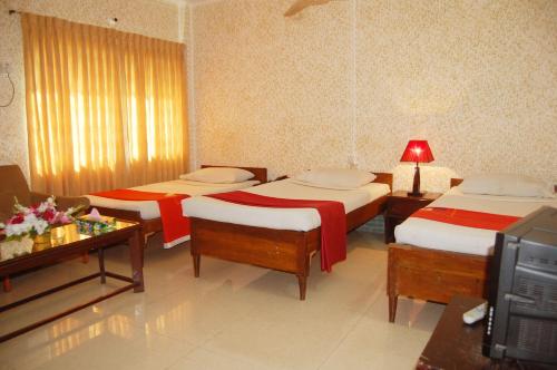 a hotel room with three beds and a television at Hotel Swiss Garden International in Chittagong