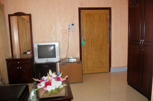 a living room with a television and a table with flowers at Hotel Swiss Garden International in Chittagong