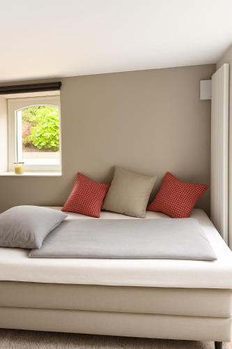 a bed with red pillows and a window at RAUM2GO - NO3 stylisches studio KURPARK & CITY in Wiesbaden