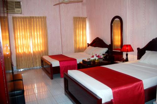 a hotel room with two beds with red and white sheets at Hotel Swiss Garden International in Chittagong