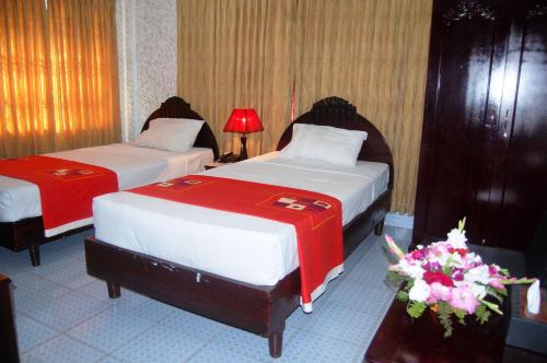 two beds in a hotel room with red and white at Hotel Swiss Garden International in Chittagong