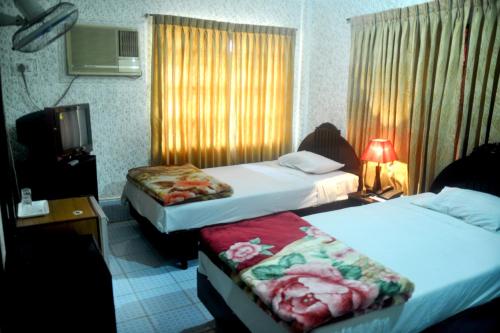 a hotel room with two beds and a window at Hotel Swiss Garden International in Chittagong