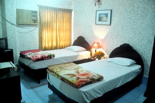 a hotel room with two beds and a window at Hotel Swiss Garden International in Chittagong