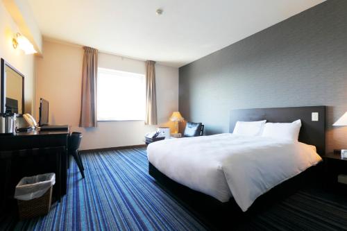 a hotel room with a large bed and a desk at Spring Sunny Hotel Nagoya Tokoname ekimae in Tokoname
