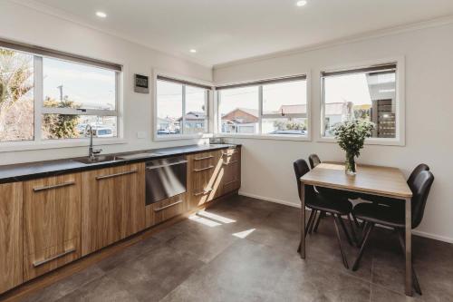 a kitchen with a table and chairs and windows at Love It On Lemon - modern townhouse near CBD in New Plymouth