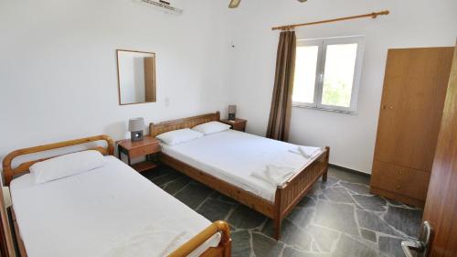 a bedroom with two beds and a window at Ampelos apartment and studios in Xerokampos
