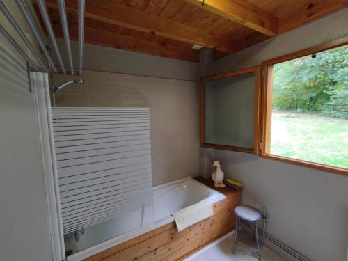 a bathroom with a tub and a window and a stool at Gîte Chalet Morvan Bourgogne in Corancy