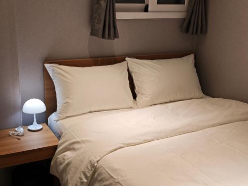 a bed with white sheets and pillows next to a desk at Unit D Hostel in Seoul