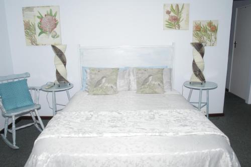 a bedroom with a white bed and two chairs at A1 Kynaston Guest House bed and breakfast or self catering in Jeffreys Bay