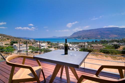 a table with a wine bottle and two chairs on a balcony at Seametry Apartments in Souda