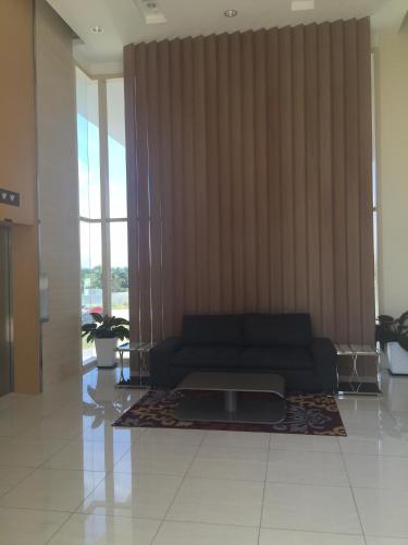 a living room with a couch in a room with windows at Afiniti Residensi Legoland Medini in Nusajaya