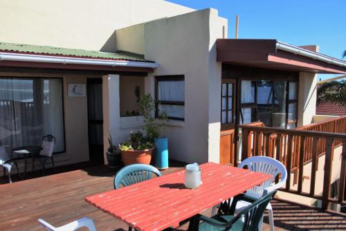 a wooden deck with a red table and chairs at A1 Kynaston Guest House bed and breakfast or self catering in Jeffreys Bay