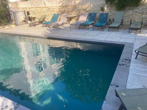 a swimming pool with chairs and a table and water at A deux pas du Rheby in Villebois
