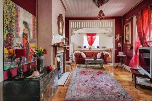 Una sala de estar con un sofá rojo y una chimenea. en Chinoiserie, en Katoomba