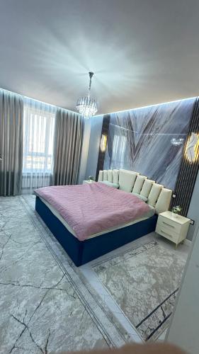 a bedroom with a king sized bed and a chandelier at Жк Тенгри in Shymkent