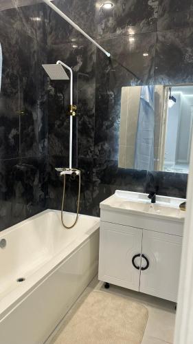 a bathroom with a white tub and a sink and a mirror at Жк Тенгри in Shymkent