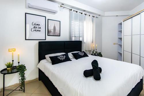 a bedroom with a large white bed with black pillows at וילת האגם - וילה מושלמת למשפחות עם בריכה פרטית in Tiberias