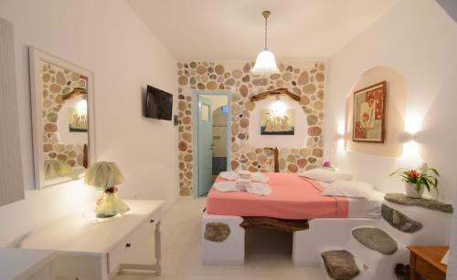 a bedroom with a bed and a table and two mirrors at Evi's Studios in Tholária