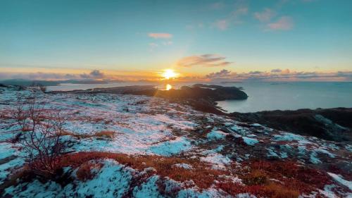 a sunset over the water with snow on the ground at Praktisk 3 roms leilighet in Bodø