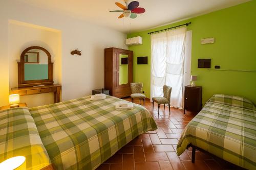 two beds in a room with green walls at Country House Maremma Nel Tufo in Pitigliano