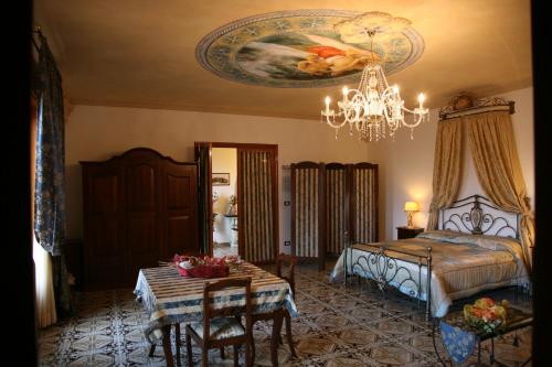 a bedroom with a bed and a table and a chandelier at Calì Nitta in Corigliano dʼOtranto