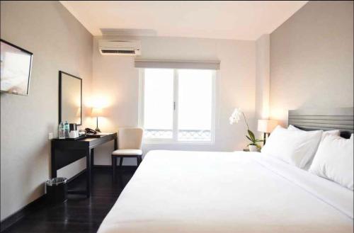 a bedroom with a large white bed and a desk at Capitol Park By Sahara Hotel in Jakarta