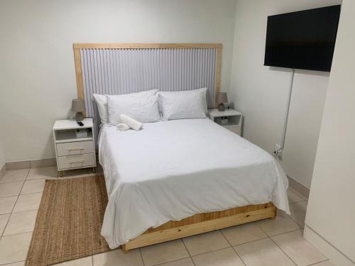a bedroom with a white bed and a television at GRACE self-catering apartments in Goodwood