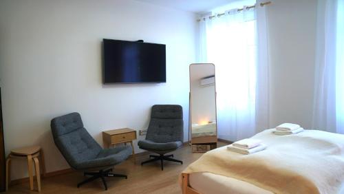 1 Schlafzimmer mit 2 Stühlen, einem Bett und einem TV in der Unterkunft Lovely&quiet, free parking, 24h self check in in Zagreb