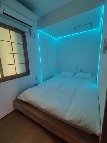 a bed in a room with a blue light at Hostel Belle Via Tokyo in Tokyo