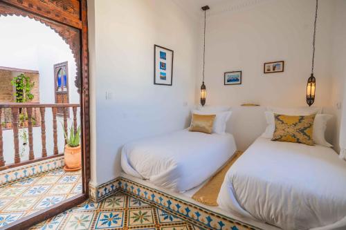 two beds in a room with a mirror at Riad Dar Irdide in Essaouira