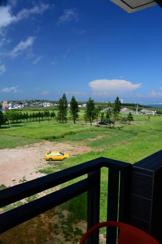 a yellow car parked in a field next to a fence at Love Door 168 in Huxi