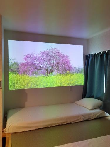 a bedroom with a large picture of a purple tree at Hostel Belle Via Tokyo in Tokyo
