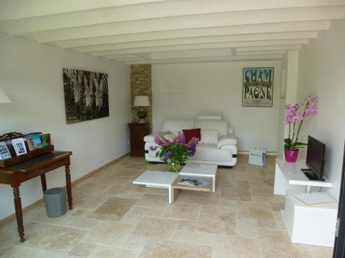 a living room with a white couch and a piano at Le Clos des Cordeliers in Sézanne