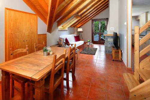 a dining room with a wooden table and a living room at PirineosNature Apartments in Plan
