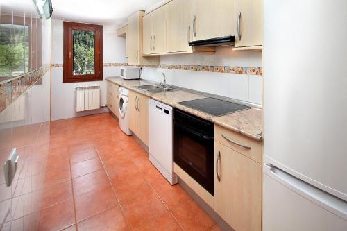 a kitchen with white cabinets and a tile floor at PirineosNature Apartments in Plan