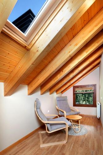 two chairs and a table in a room with wooden ceilings at PirineosNature Apartments in Plan