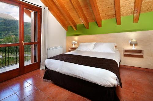 a bedroom with a large bed with a green wall at PirineosNature Apartments in Plan