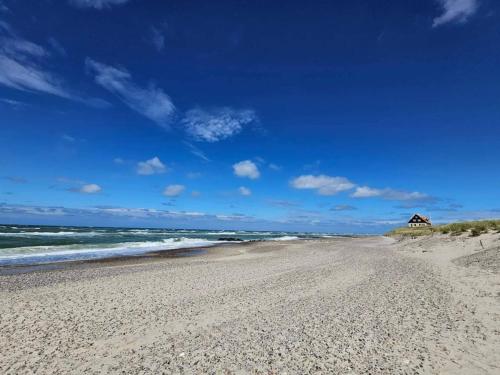 a sandy beach with a house in the distance at 6 person holiday home in Skagen in Skagen