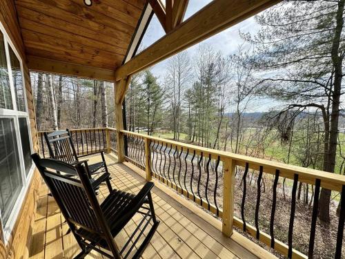 a porch with two rocking chairs on a balcony at Alone At Last - New LUX - WiFi - Hot Tub in High Falls