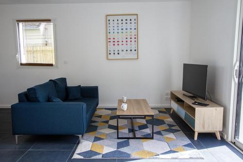 a living room with a blue couch and a tv at Appartement Neuf - Port de l'AberWrac'h - in Landéda